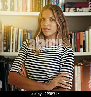 She means business. Portrait of a woman standing in front of bookshelves in her home office. Stock Photo