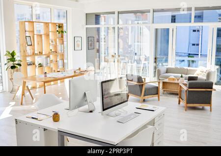 Empty office room, workplace or interior with an arranged desk, computers and furniture. Corporate organized work space, business company working area or modern headquarters workspace Stock Photo