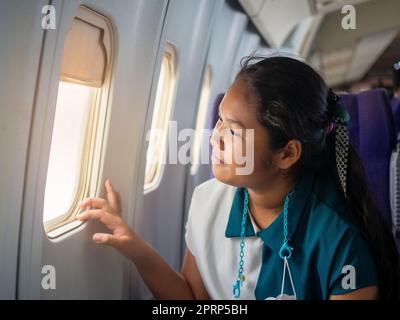 Asian woman sitting looking out of plane window Stock Photo