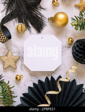 Blank gift tag between black and golden Christmas decorations, top view, Mockup Stock Photo