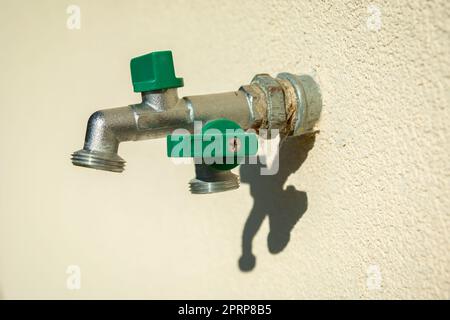 A double brass garden faucet mounted in the bright wall Stock Photo