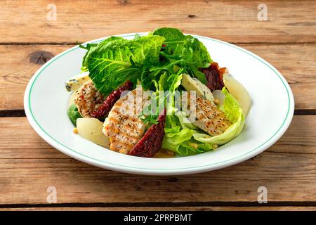 Salad with roasted turkey, dried tomato, gorgonzola, canned pear and pine nuts Stock Photo
