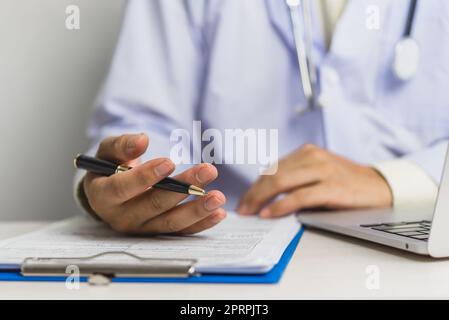 Doctor hand holding pen write and paperwork document patient treatment on clipboard.Business health care concept. Stock Photo