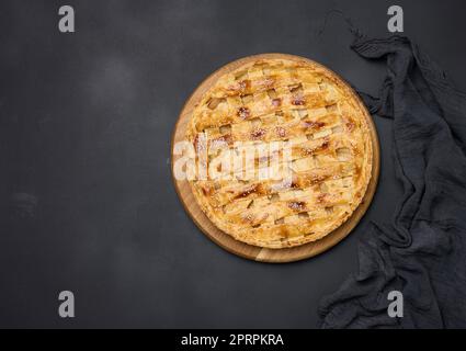 Round baked apple pie on a black table. View from above Stock Photo