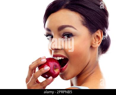 Biting into her favorite snack. Studio portrait of a young woman biting into an apple. Stock Photo