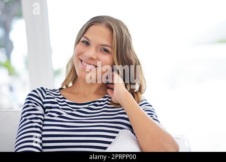 Weekends are all about relaxaing. Portrait of an attractive young woman sitting on the sofa at home. Stock Photo