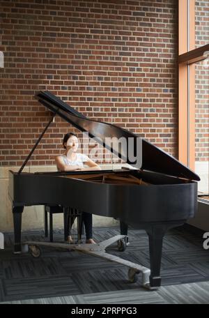 Play first by the rules and then by your heart. a pianist sitting at her piano. Stock Photo