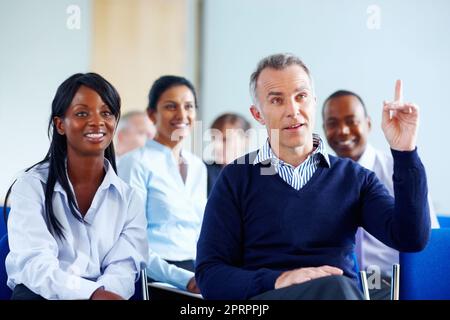 I have a question. Business man raising his finger within group of executives. Stock Photo