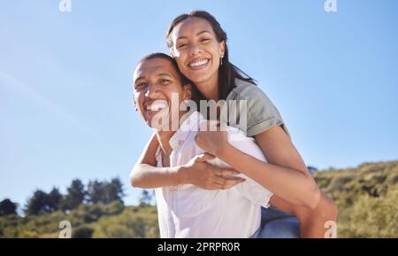 Love, happy couple and travel adventure with young lovers out hiking, exploring and traveling through nature in summer. Portrait smile of latino man and woman enjoying piggyback while out for a walk Stock Photo