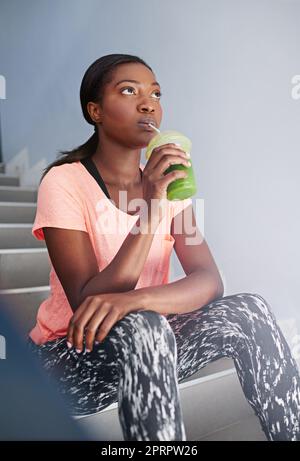 Daydreaming on a workout break. an attractive young woman drinking juice while exercising outdoors. Stock Photo