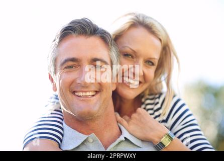 Shes my partner in play. Cropped portrait of a handsome mature man piggybacking his wife in the park. Stock Photo