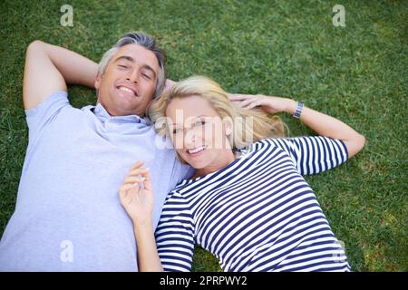 Relaxing in the park. High angle portrait of a mature couple lying in the park. Stock Photo