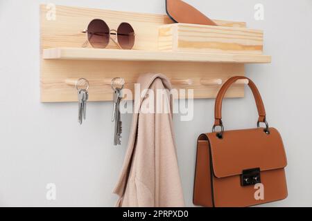 Wooden hanger for keys with different stuff on light grey wall Stock Photo