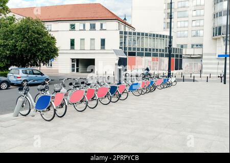 Many bicycles and station on city street. Bike rental fleet Stock Photo