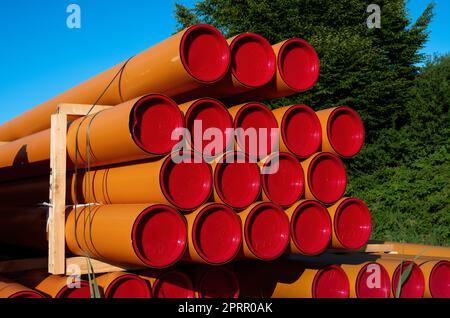 Stack of orange pvc protective pipes Stock Photo