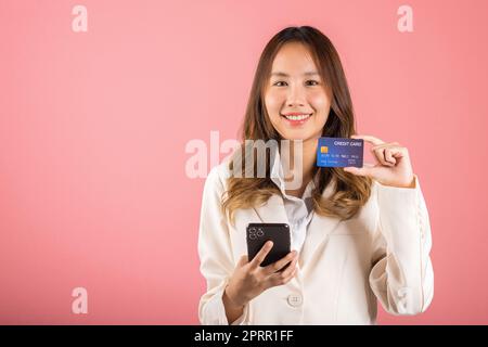 young woman excited smiling hold mobile phone and plastic debit credit bank card Stock Photo