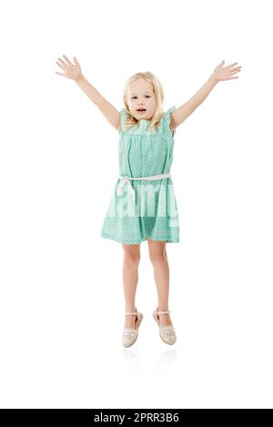 Reach for the sky. Studio shot of a cute little girl jumping for joy against a white background. Stock Photo