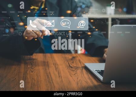 Businessman using a laptop and touching Contact us or Customer support hotline on virtual screen. Stock Photo