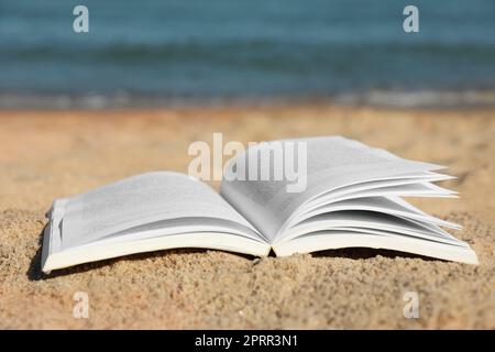 Open book on sandy beach near sea Stock Photo