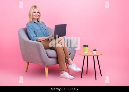 Photo of attractive confident senior lady worker use netbook sit armchair office wear casual clothes isolated pink color background Stock Photo