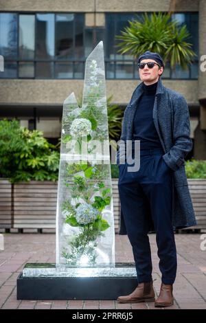 London, UK.  27 April 2023.  Scottish composer and conceptual artist Erland Cooper alongside ‘Glacier’, his tall melting ice sculpture, in the Barbican’s Sculpture Court with which he will remain until it melts.  His slow-protest examines the nature of climate change and comes ahead of his upcoming album ‘Folded Landscapes’, which will raise funds for Brian Eno’s EarthPercent charity.  Credit: Stephen Chung / EMPICS / Alamy Live News Stock Photo