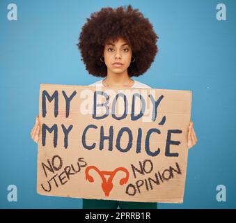 Protest, human rights and woman with a poster for abortion, body freedom and justice against a blue studio background. Choice, equality and portrait o Stock Photo