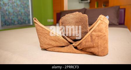 Yellow towel on bed decoration in bedroom interior, Freshly laundered fluffy towels, Towel in hotel room, Beautifully folded toiletries Stock Photo