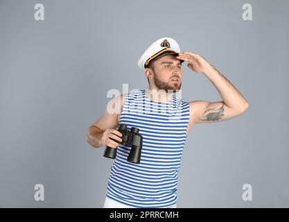 Sailor with binoculars on light grey background Stock Photo
