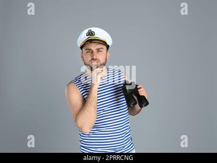 Thoughtful sailor with binoculars on light grey background Stock Photo