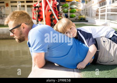 Dad and child boy hugging piggyback ride, spring banner. Childhood and parenthood kids concept. Happy father and son playing together outdoor. Stock Photo