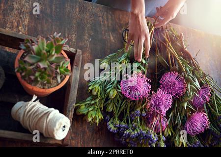 Every flower is a soul blossoming in nature. a pretty floral bouquet being completed on a wooden counter top. Stock Photo