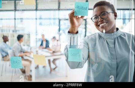 Black woman, post it writing and schedule planning in global business office, marketing startup and creative company. Smile, happy and teamwork leader in meeting with training timeline notes on wall Stock Photo