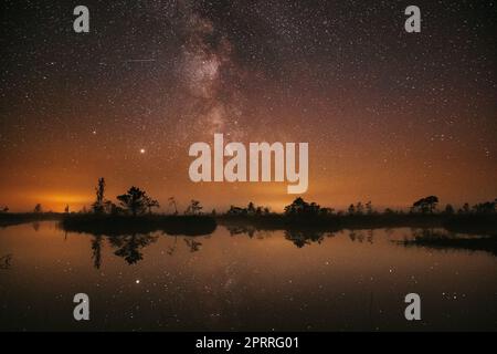 Swamp Bog Marsh Wetland Lake Nature Night Landscape. Night Starry Sky Milky Way Galaxy With Glowing Stars And Moon. Nature Night Sky Reflection In Water. Yelnya Swamp In Belarus Stock Photo