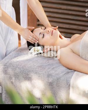 Perfectly peaceful. A young woman getting a face massage from a massage therapist. Stock Photo
