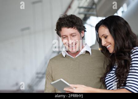 Everything looks good. two coworkers standing in an office looking at a digital tablet. Stock Photo