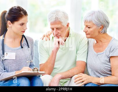 Youll need specialised care for this...A doctor explaining medical care to a senior patient and his spouse. Stock Photo