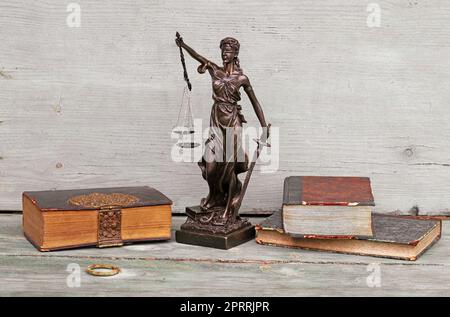 Justice figure and old books on a wooden background. Justice, scales and court Stock Photo