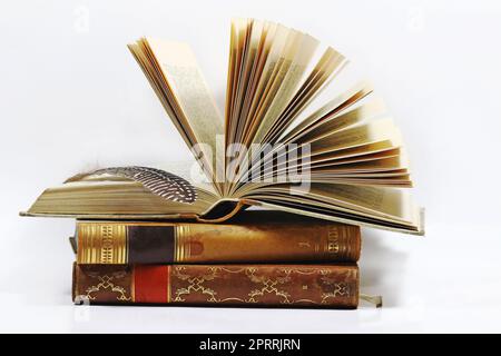 Three old books and a pen against a white background Stock Photo