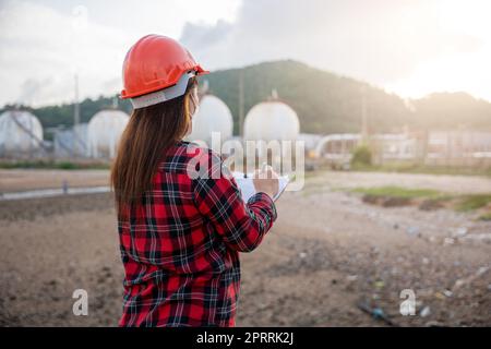 Happy Asian worker woman in oil chemical industry working visual inspection list on clipboard in plant Stock Photo