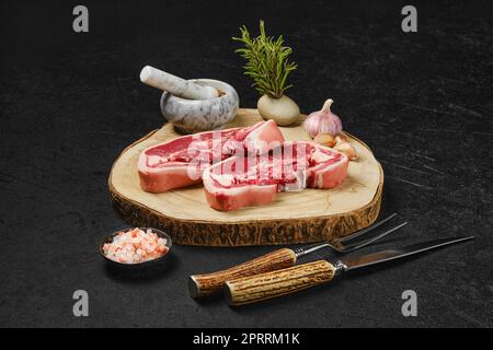 Raw lamb double loin chop with meat fork, herb and spices Stock Photo