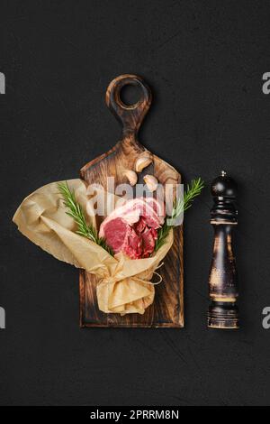 Raw lamb double loin chop wrapped in paper on wooden cutting board Stock Photo