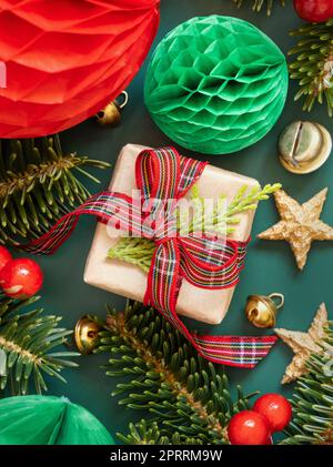 Wrapped gift boxes between Christmas decorations and green fir branches on green Stock Photo