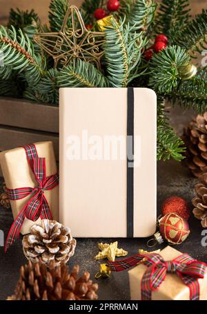 Hardcover notebook between christmas decorations, fir branches and pine cones close up Stock Photo