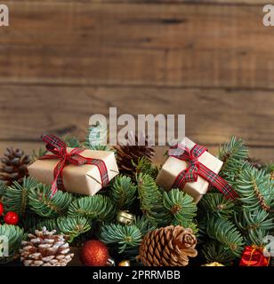 Wrapped gift boxes on reen fir branches near Christmas decorations and pine cones Stock Photo