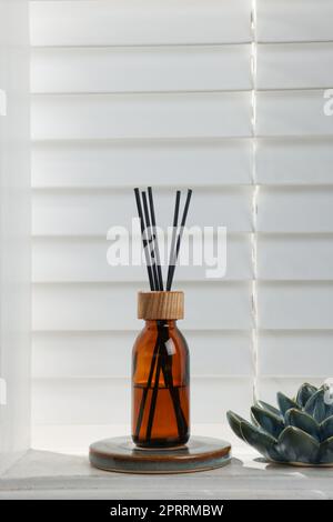 Air reed freshener and ceramic decor on white table near window Stock Photo