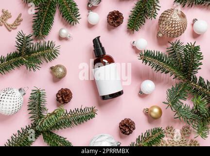 Cosmetic one pump Bottle near Christmas decorations, fir branches and pine cones on pink, mockup Stock Photo