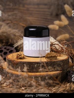 Cream jar with blank label on wood near natural decorations close up. Packaging Mockup Stock Photo