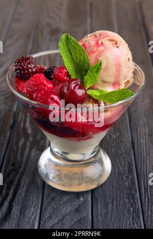 A cup of cherry ice cream decorated with raspberries and dewberry and mint leaves Stock Photo