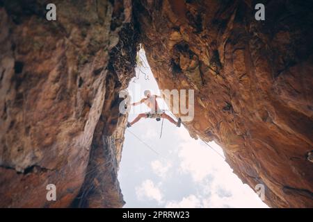 Mountain or rock climbing, cliff hanging and adrenaline junkie with courage on adventure trying to balance between gap. Athletic climber man doing fitness, exercise and workout during extreme sport Stock Photo