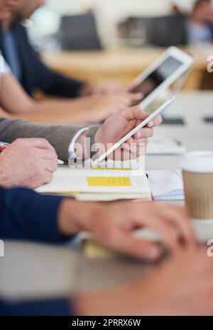 Let technology do the thinking. a group of business professionals sitting around the table in a meeting while using modern technology. Stock Photo